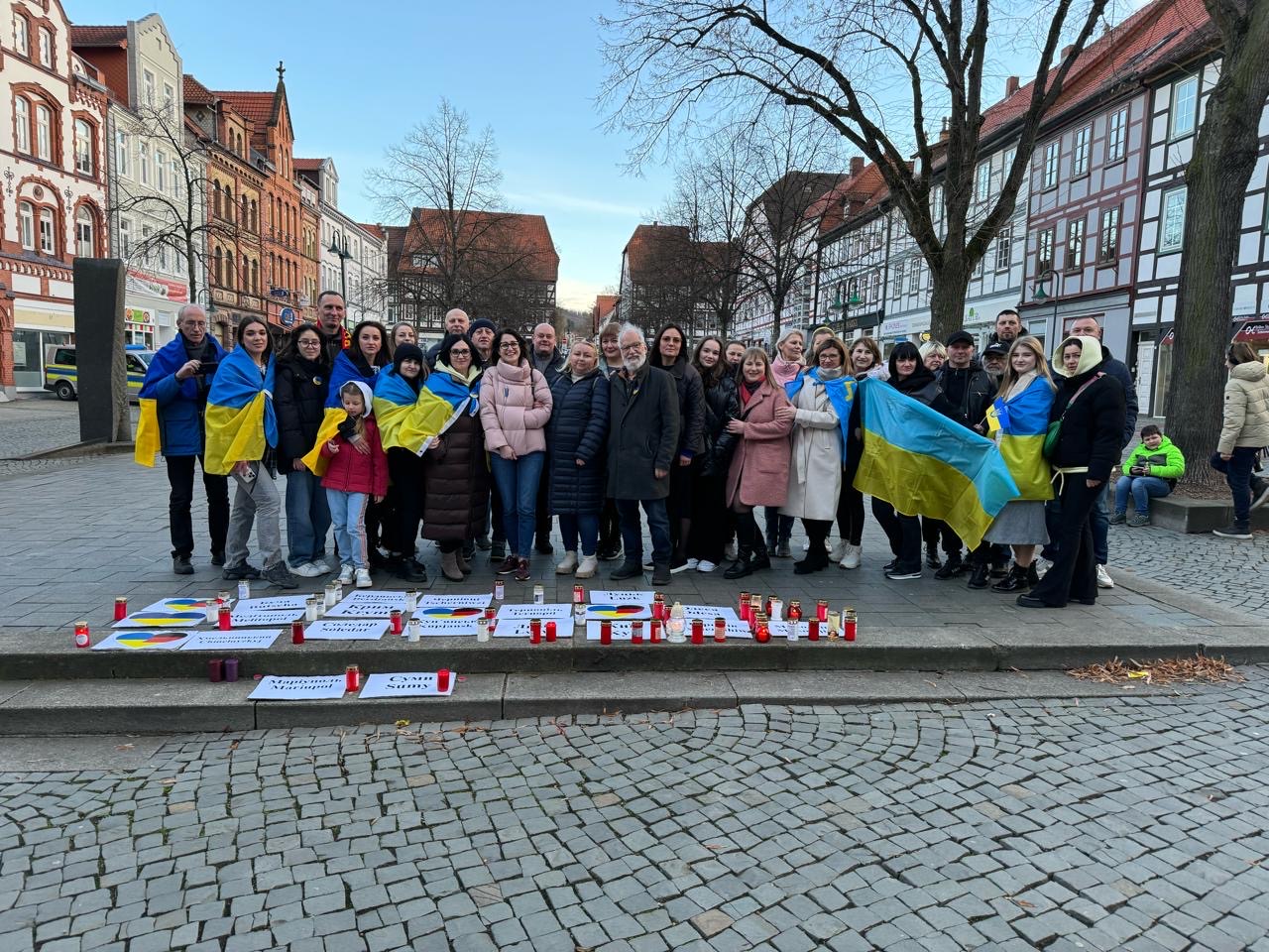 Gruppenphoto: Ukrainer und Deutsche stehen, mit einer Ukrainefahne, auf dem Northeimer Marktplatz. Vor ihnen liegen Schilder und Kerzen.