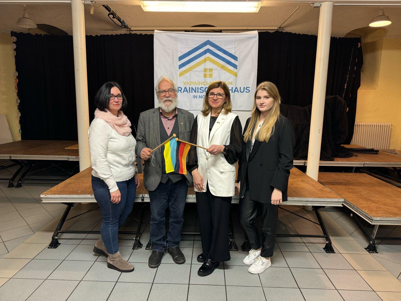 Unser Vorstand: Der Vorstand des Ukrainischen Hauses Northeim bestehend aus (von links nach rechts) Yuliya Divivi (Vorsitzende), Hans Harer (2. Vorsitzender), Iya Hehn (Kasse) und Alina Divivi (Schriftführerin). Iya Hehn und Hans Harer halten eine Deutschland- und eine Ukrainefahne aneinander.